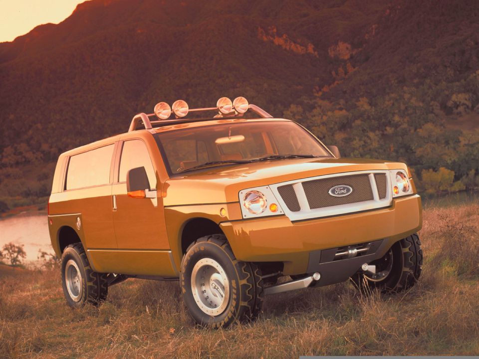 Orange Ford Bronco concept SUV with roof rack and spotlights parked in a grassy field