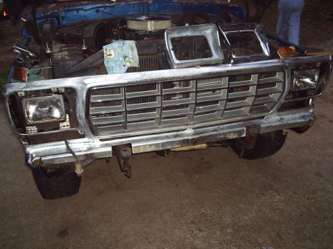 1978 Ford Bronco - The front end of a blue Ford truck is shown with the hood up and the grille removed for repair.