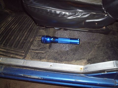1978 Ford Bronco - A blue anodized Maglite flashlight lies on the black bedliner-coated floor of a truck cab, shot through the open door. A ribbed rubber floo…
