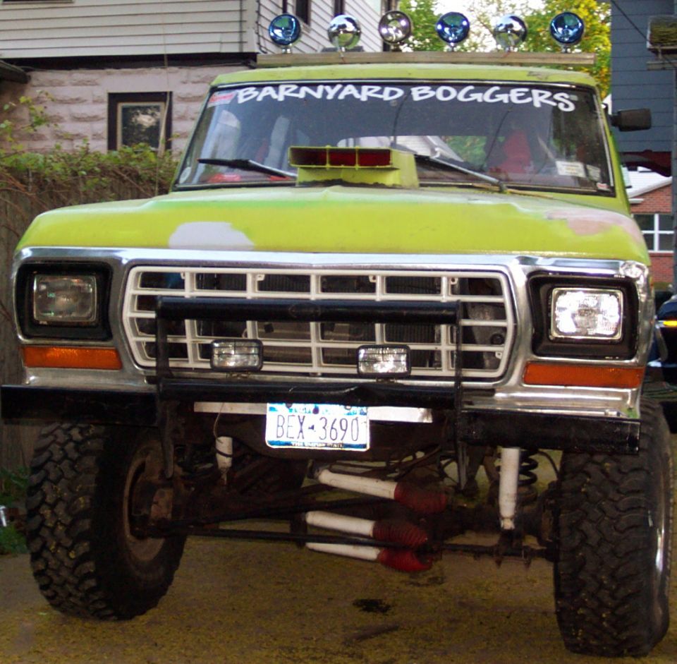 Front view of a lifted lime green pickup truck with a snorkel, off-road lights, and "BARNYARD BOGGERS" sticker on the windshield