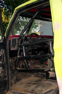 1978 Ford Bronco - Interior view of a yellow vehicle, a prominent black roll cage and the SuperMotors logo visible at the bottom.