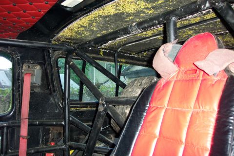1978 Ford Bronco - The interior of a heavily modified vehicle shows a roll cage, racing seats, and a spare tire mounted inside.