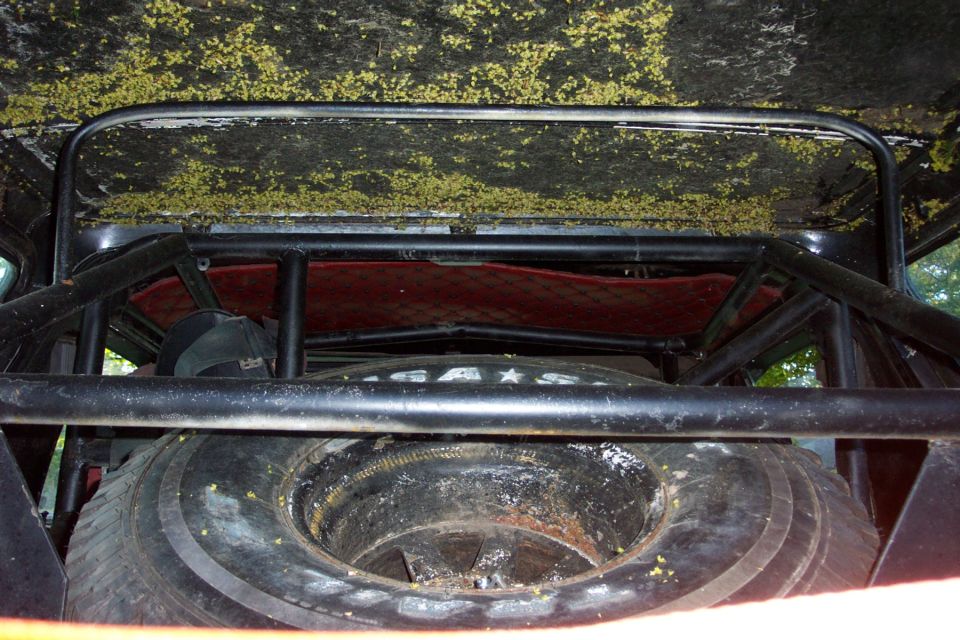 Spare tire and roll cage inside a vehicle with a dirty, textured ceiling