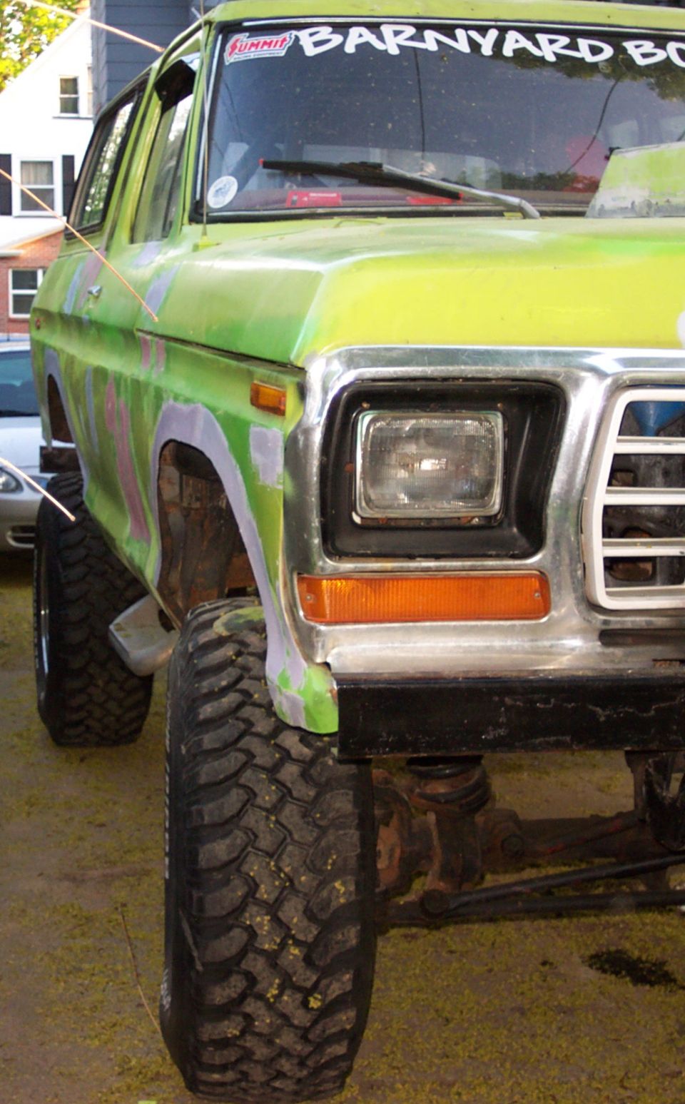 Green Ford Bronco with large tires and custom paint, front 3/4 view