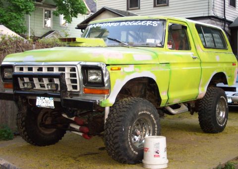 1978 Ford Bronco - This modified 1978 Ford Bronco features a prominent hood scoop and lifted suspension, with visible bodywork in progress.