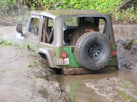 1980 Ford Bronco - This Jeep Wrangler is deeply stuck in mud, with its rear end submerged in water.