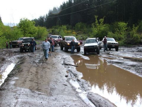 1980 Ford Bronco - Multiple off-road vehicles are stuck in a muddy, wet terrain.