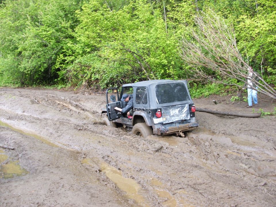 Black Jeep Wrangler stuck in mud with driver inside