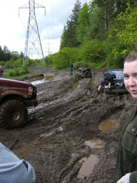 1980 Ford Bronco - Several vehicles are stuck in the mud on a trail under power lines.