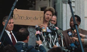1986 Ford Bronco - Man holds sign at press conference surrounded by microphones and reporters.
