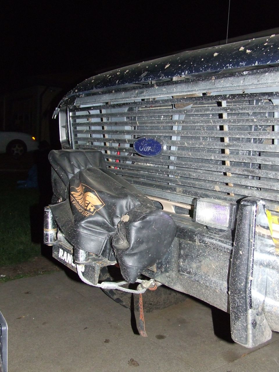 Front grille and bumper of a dark blue Ford Bronco with a black cover over a winch