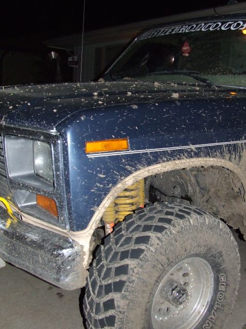 1986 Ford Bronco - Front corner of a mud-splattered 1986 Ford Bronco shows off its off-road tires and suspension.