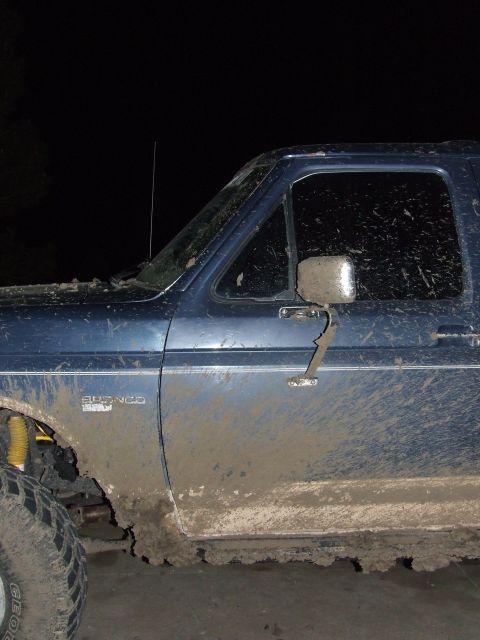 1986 Ford Bronco - Mud-covered 1986 Ford Bronco shown from the side, with visible damage to the side mirror.