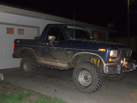 1986 Ford Bronco - This lifted Ford Bronco is covered in mud, suggesting recent off-road use.