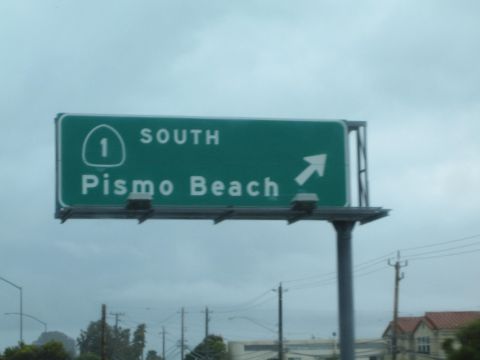 1990 Ford Bronco - Green freeway guide sign marking Route 1 South toward Pismo Beach with an up-right exit arrow under an overcast sky.