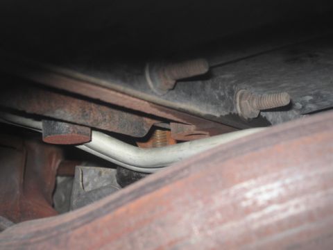 2000 Jeep TJ - Close-up view of the undercarriage, showing an exhaust pipe and several rusted bolts.