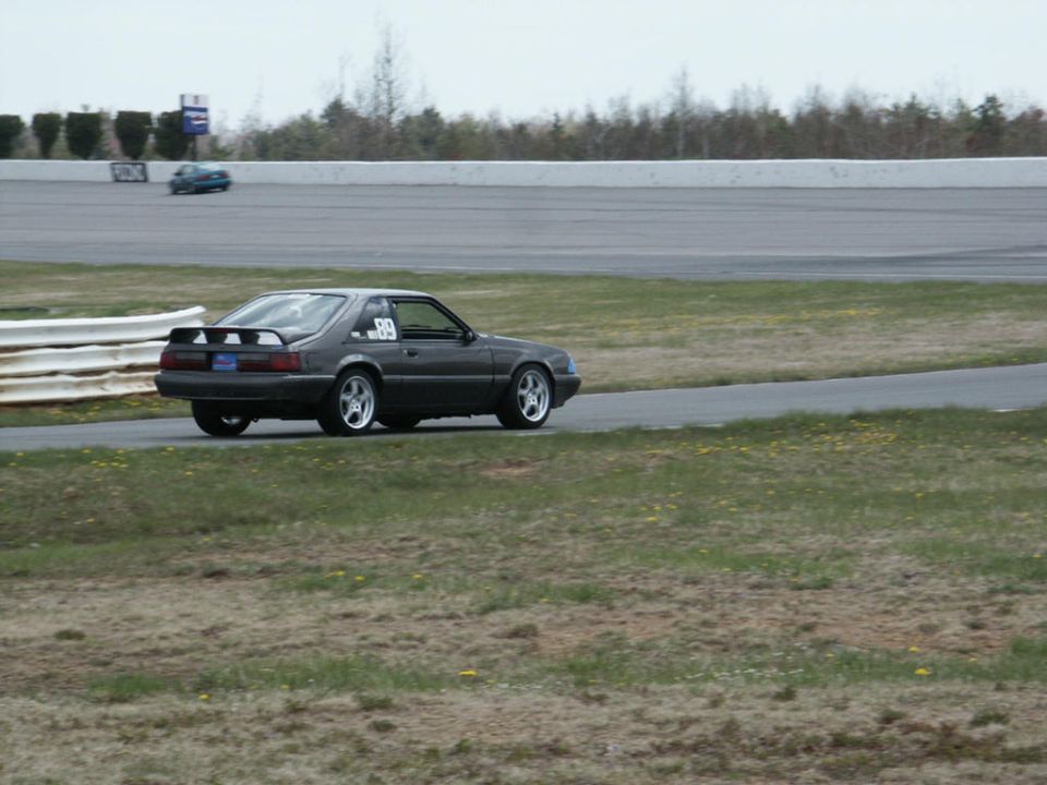 Dark gray Ford Mustang with racing number 89 on door, on a race track