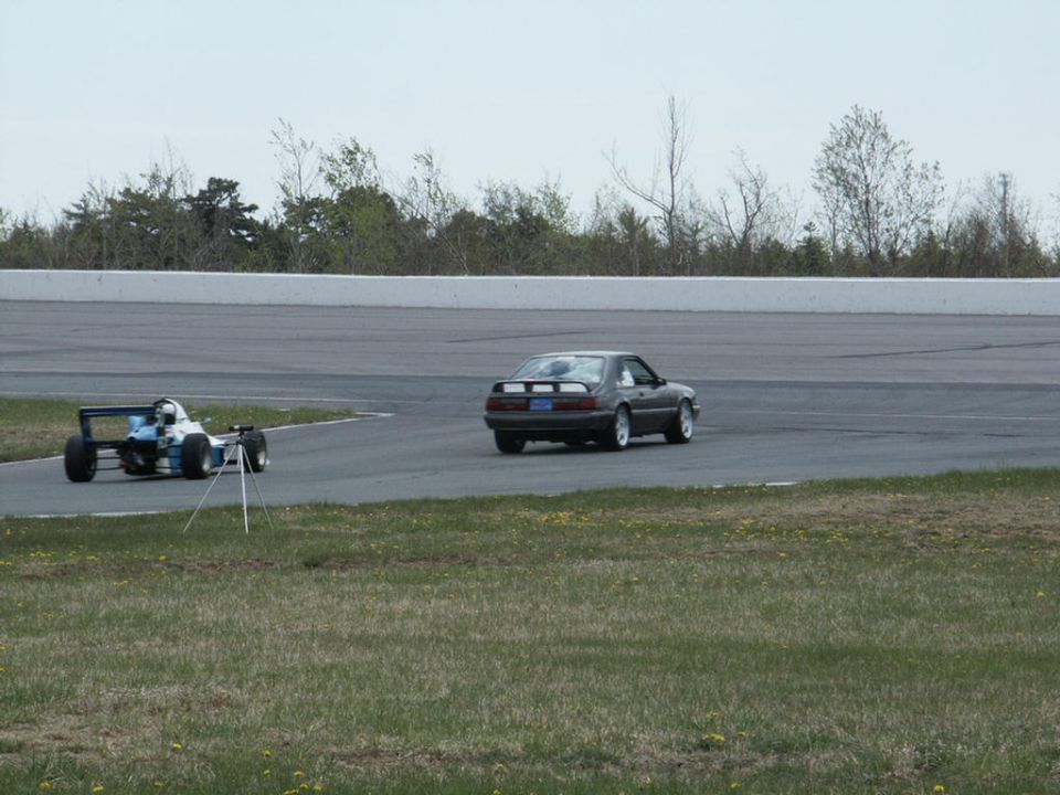 Dark sedan with a spoiler on a racetrack, rear view