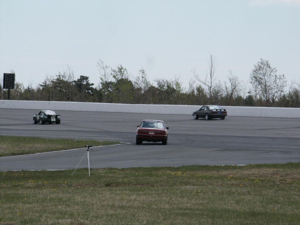 three cars racing on a track, one in foreground, two further ahead