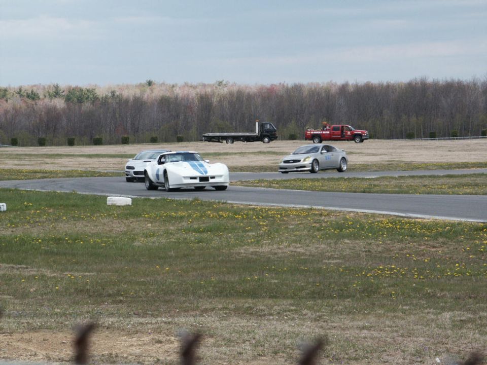 White race car with blue stripes on a track, side view