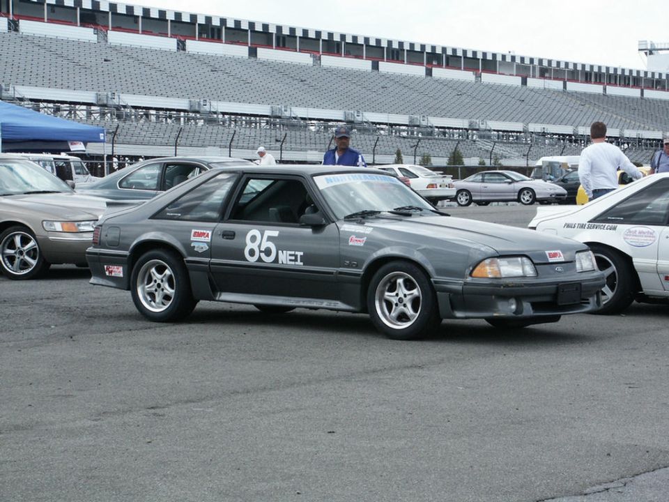 Gray Ford Mustang with number 85 on door, parked at a racetrack