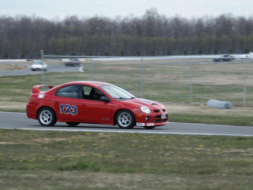 Red Dodge Neon SRT-4 with number 123 on the door, on a race track