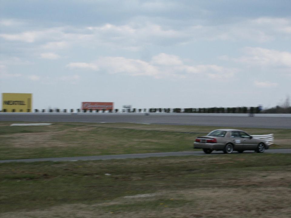 Tan 2001 Mercury Grand Marquis with a large white spoiler on a race track