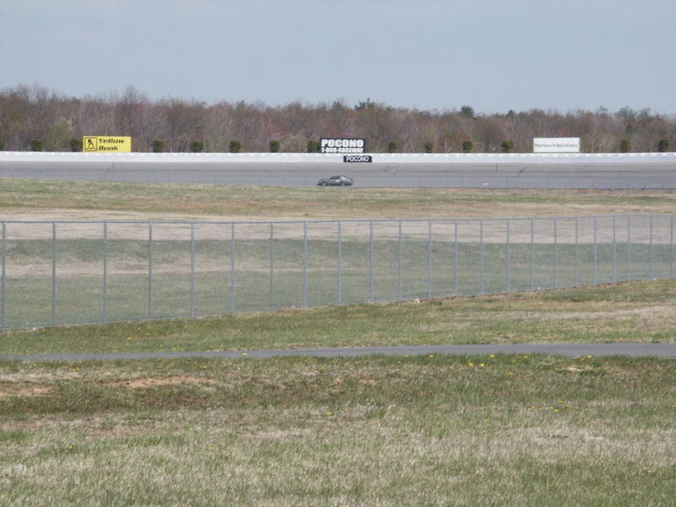 Car on a race track with 'Pocono' signs in the background