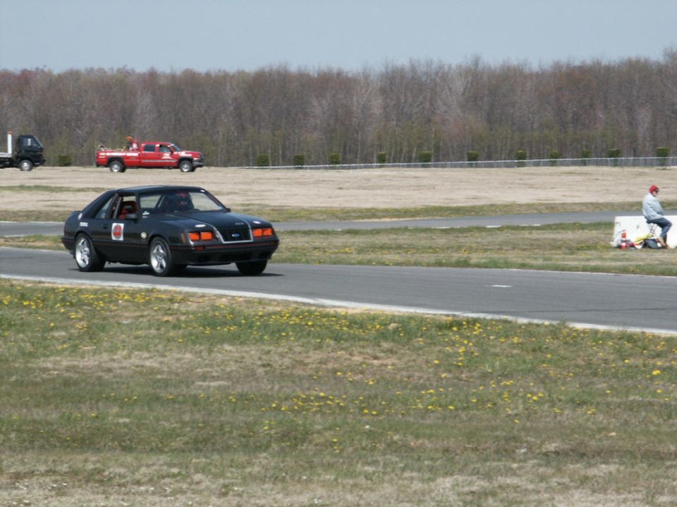 Black coupe with racing decals on a track, front 3/4 view