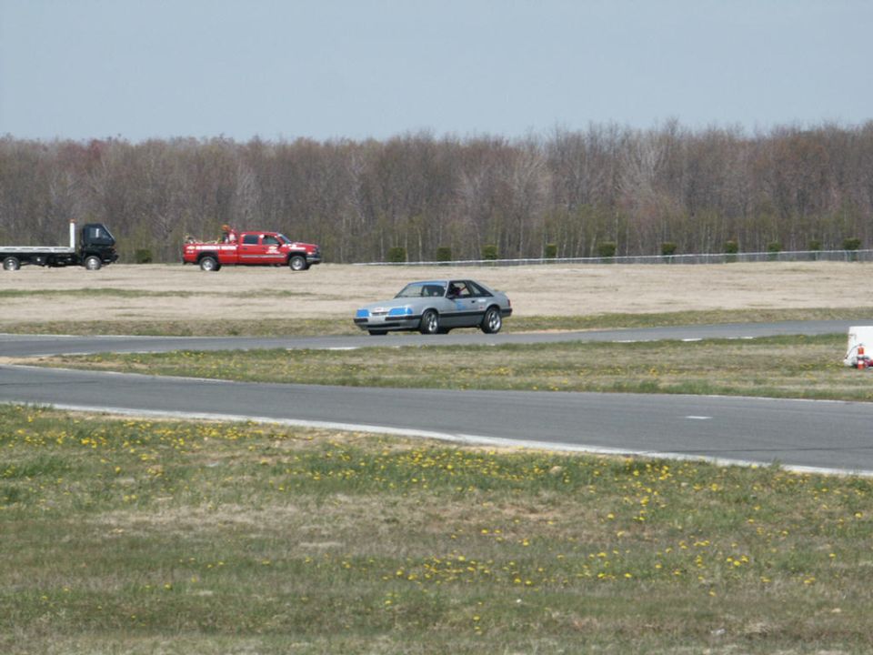 Silver coupe with blue accents on a race track, viewed from the side