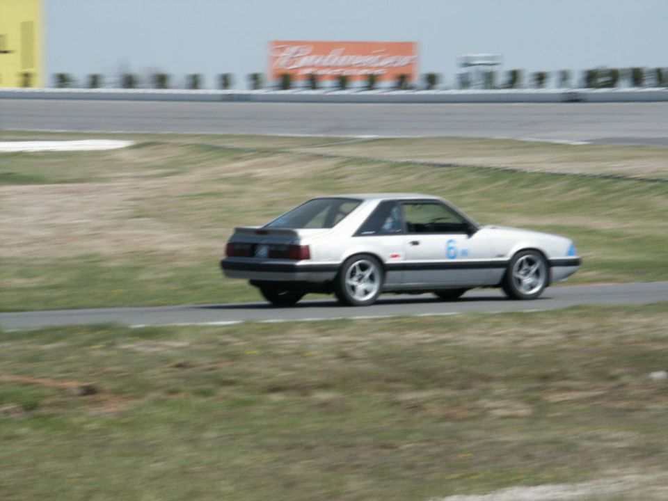 White coupe with racing number 6 on door, driving on asphalt track