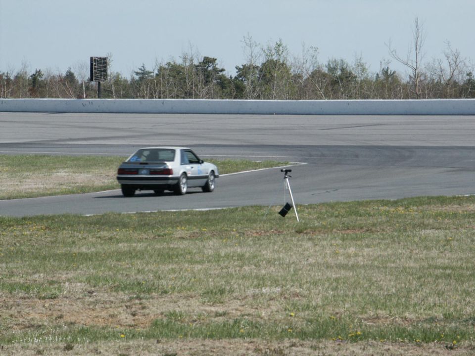 Silver coupe with a dark rear panel on a race track, rear view