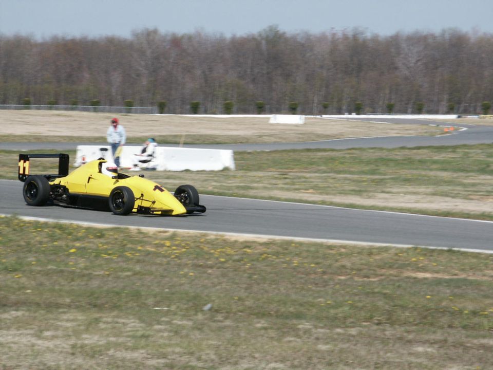 Yellow open-wheel race car with number 11 on the rear wing, on a paved track