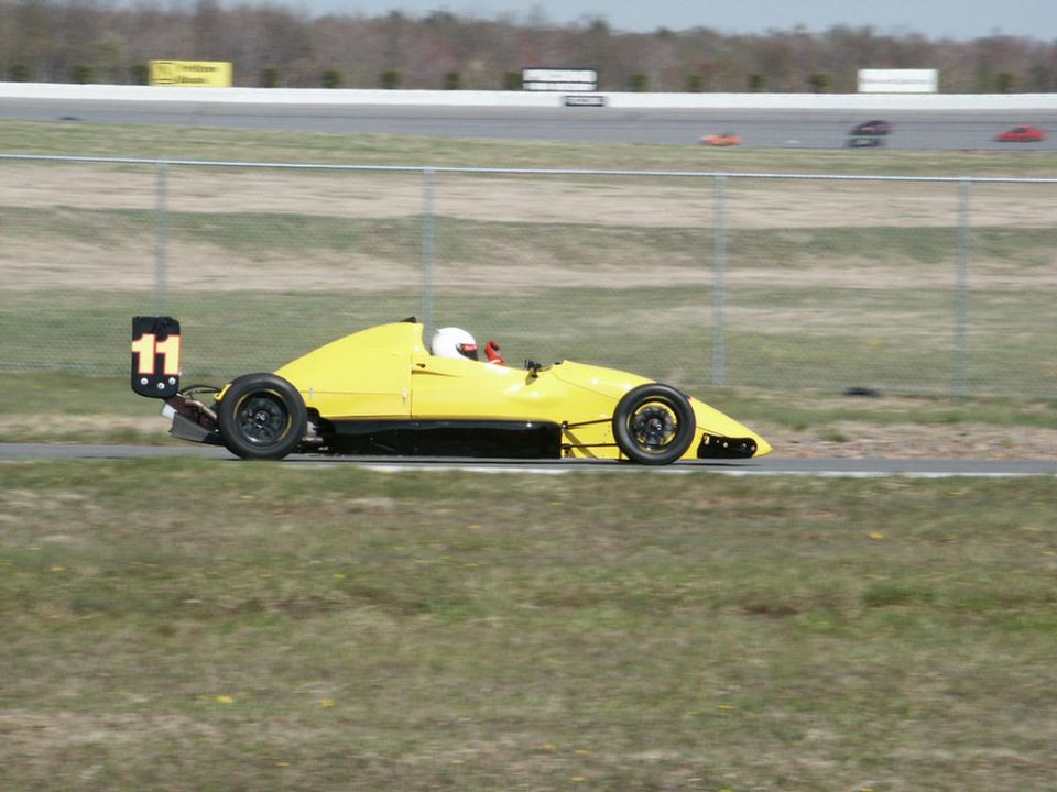 Yellow formula race car with number 11 on the rear wing, on a track