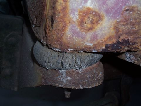 1978 Ford Bronco - Close-up of a heavily rusted body mount a cracked rubber isolator, likely from an older vehicle.