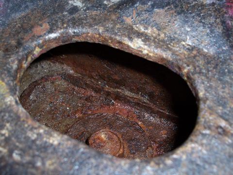 1978 Ford Bronco - A close-up view of a corroded metal opening, revealing internal components and significant rust.