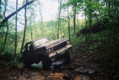 1978 Ford Bronco - A Ford Bronco tackles a challenging off-road course in a wooded area.