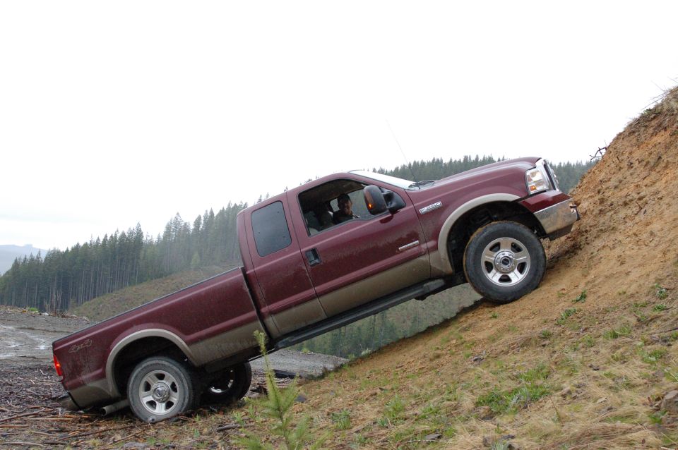 Maroon Ford Super Duty extended cab pickup climbing a steep dirt bank