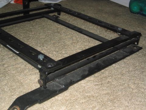 1993 Ford Probe - A black metal seat bracket with adjustable sliders is shown on a carpeted surface.