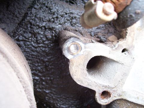 1984 Ford Bronco - Engine part with oil residue and a visible bolt hole.