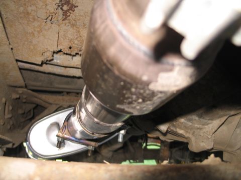 1995 Ford Bronco - Underside view of a vehicle's exhaust system, highlighting the muffler and piping with visible rust on the chassis.