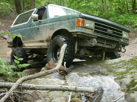 1990 Ford Bronco - This 1990 Ford Bronco is navigating a challenging off-road course with water and rocks.