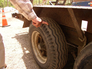 1995 Ford Bronco - Close-up of a trailer tire, showing its tread pattern and a person's hand.