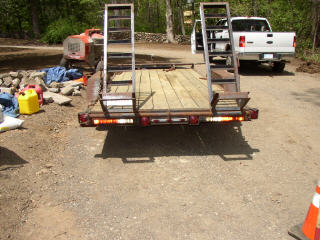 1995 Ford Bronco - A trailer is hitched to a white pickup truck, with construction equipment visible in the background.