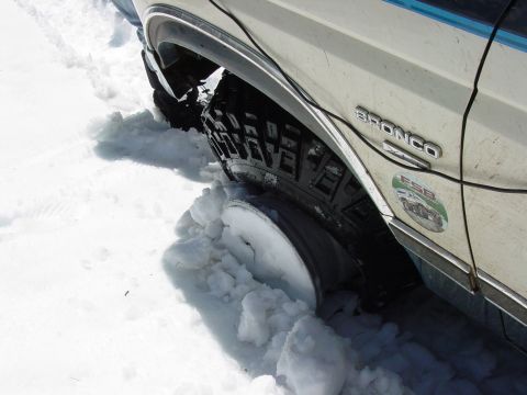 1986 Ford Bronco - 1986 Ford Bronco stuck in snow, showing the side and wheel.