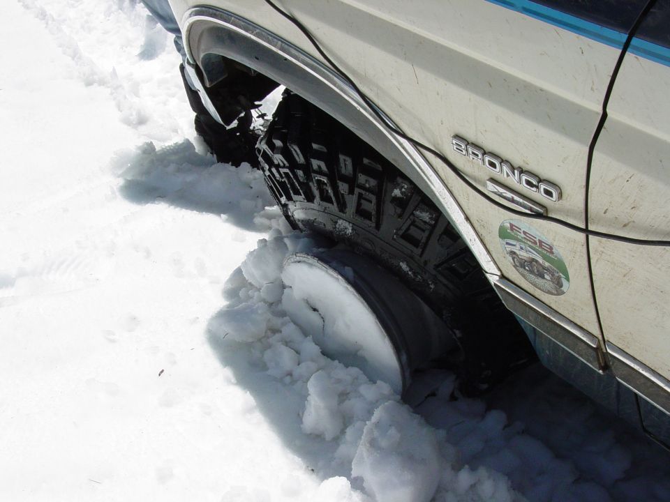 1986 Ford Bronco stuck in snow, wheel deep in snow