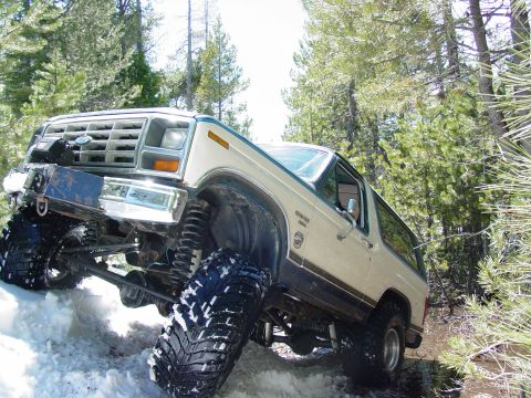 1986 Ford Bronco - This lifted Ford Bronco navigates a snowy and muddy trail through a forest.