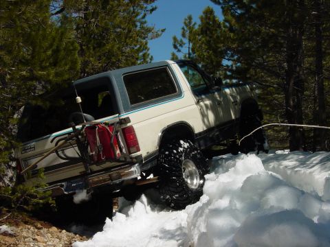 1986 Ford Bronco - This Ford Bronco is navigating a challenging snowy terrain with its off-road tires.