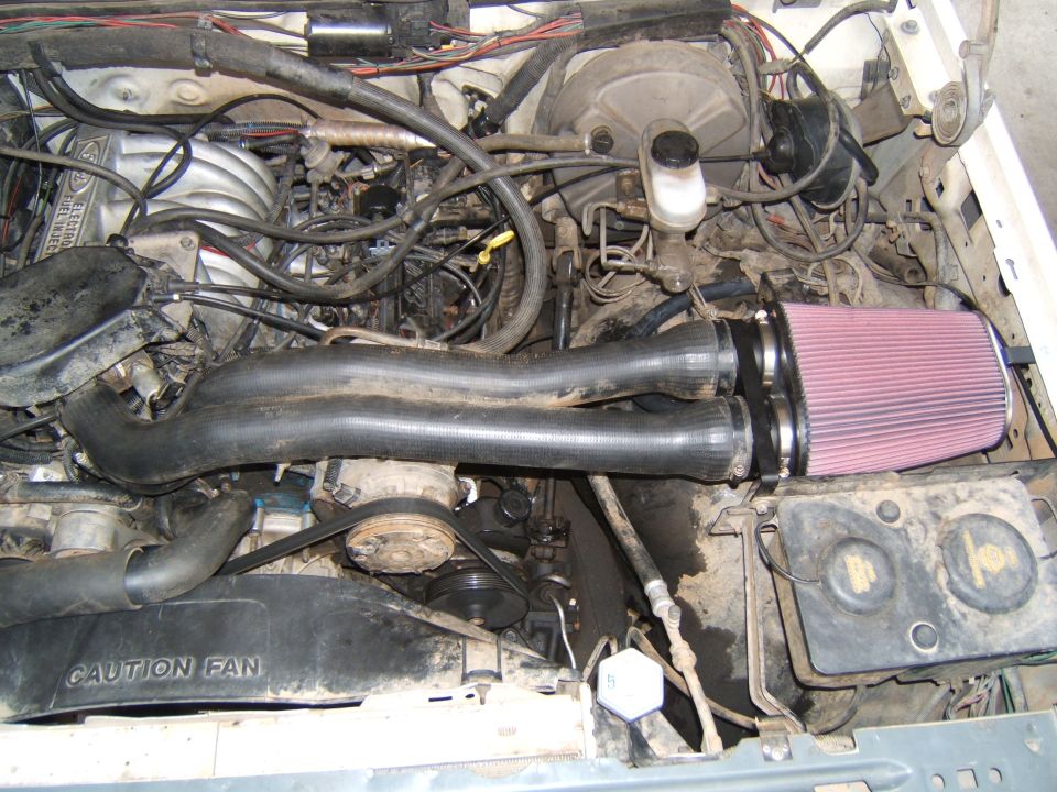 Engine bay with a black intake tube and red conical K&N-style air filter installed