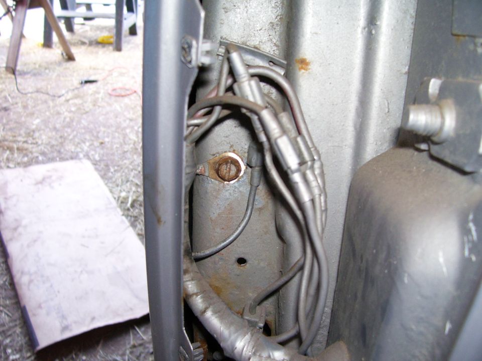 Close-up of vehicle wiring harness and a rusty mounting bracket